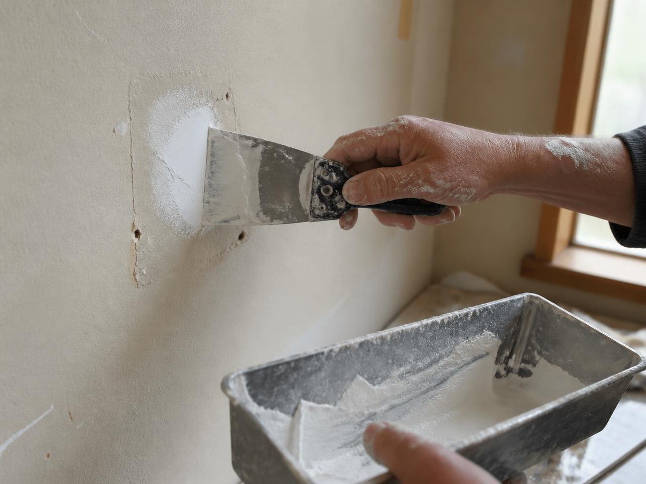 Taping knife feathering joint compound over a drywall patch during drywall repair near me in San Diego